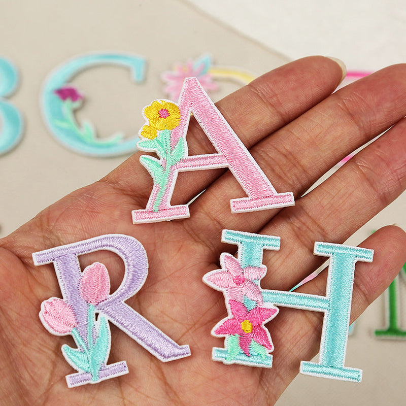 floral alphabet embroidered stick-on patches held in hand