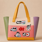 black and white cat with goldfish bowl stick-on patches decorating a colorful color-block leather handbag
