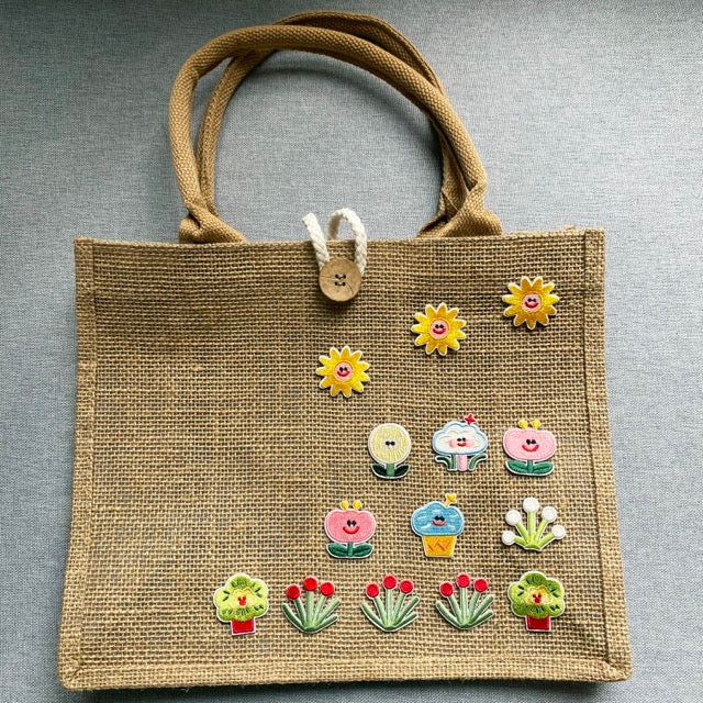 assorted botanical embroidered patches arranged as a garden on a burlap tote bag