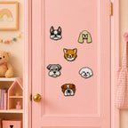 realistic dog face patches including black french bulldog orange pomeranian gray schnauzer cream cocker spaniel fluffy bichon and wrinkled bulldog on a pink door in a pastel room