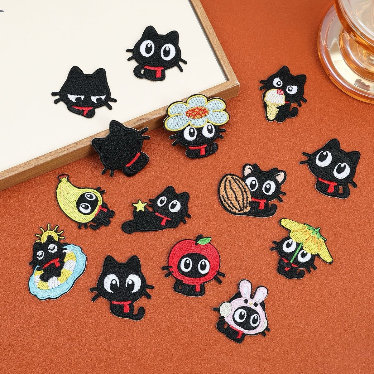 Fourteen red scarf black cat embroidered stick-on patches with playful costumes, poses, and accessories
