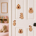 six capybara embroidered patches in various poses stuck on a white door in a pink kids room