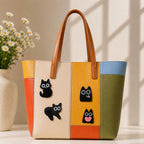 black cat with oversized round eyes in sitting lying square and heart-hugging poses stick-on patches decorating a multicolor stripe leather handbag
