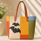 large and small black gothic bat with textured wings stick-on patches decorating a multicolor stripe leather handbag