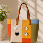 white black orange and grey cat face with gold border stick-on patches decorating a multicolor stripe leather handbag