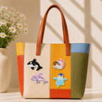 orca dolphin nautilus shell and penguin stick-on patches decorating a multicolor stripe leather handbag