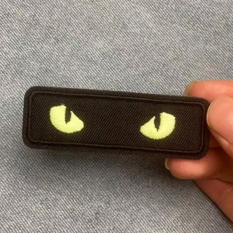 glow-in-the-dark cat eye embroidered stick-on patches held in hand