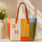 minimalist alphabet patches G H I K on a bold orange yellow and green color-block leather tote bag