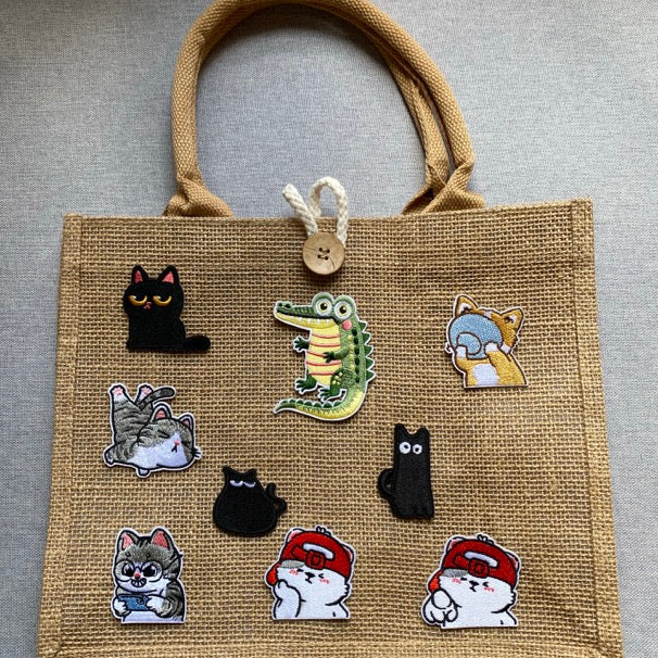 hungry and sleepy cat embroidered stick-on patch on a jute tote bag