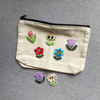 assorted googly eyes floral embroidered patches on a natural canvas pouch