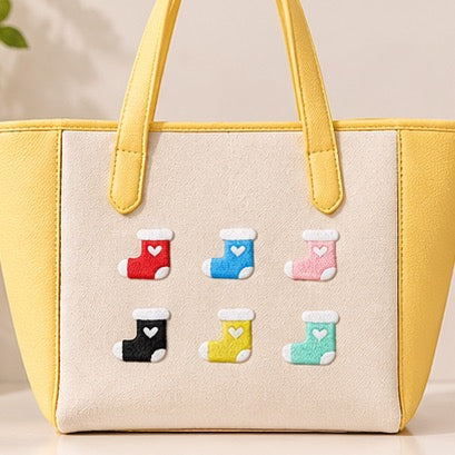 cute heart stocking embroidered stick-on patches on yellow canvas tote bag — six colour stockings arranged in a grid red sky blue coral pink black yellow mint green