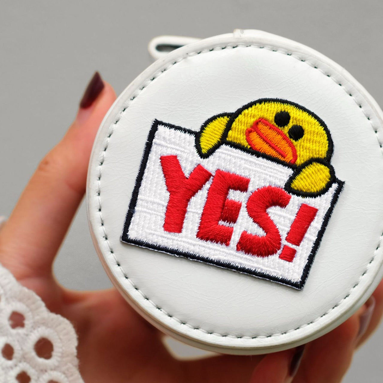 yes  duck embroidered patch sticker on a small round crossbody bag