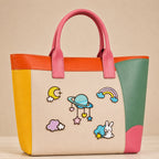 moon saturn rainbow cloud and bunny with stars stick-on patches decorating a pink and orange color-block leather handbag