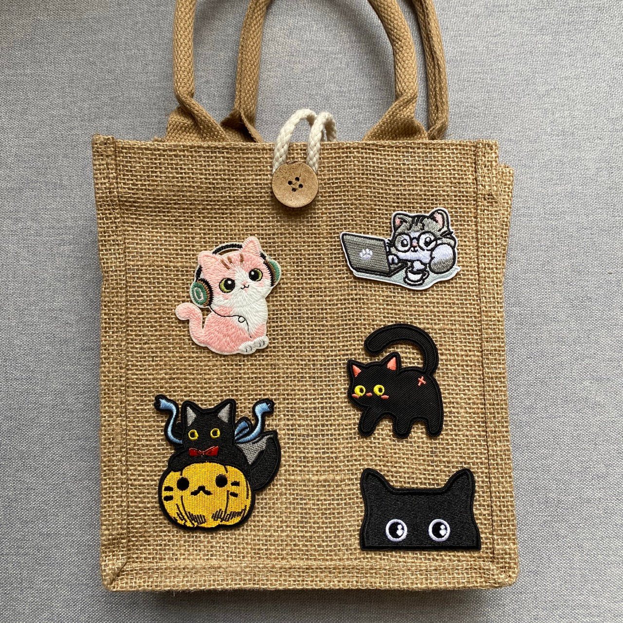 peeking cat embroidered stick-on patch on a jute bag