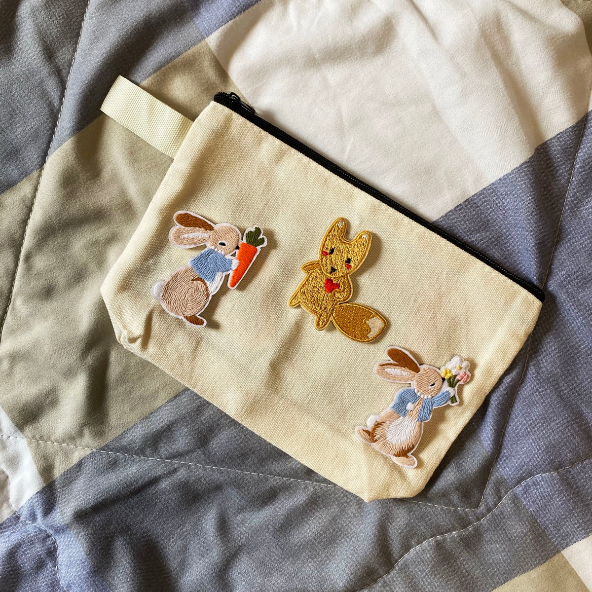 Cream zippered pouch decorated with carrot bunny, flower bunny, and red-heart fox embroidered patches
