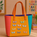 colorful mini angel wing stick-on patches decorating an orange and yellow color-block leather handbag
