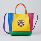 Chinese lion dance embroidered patch on a bold color-block leather tote bag