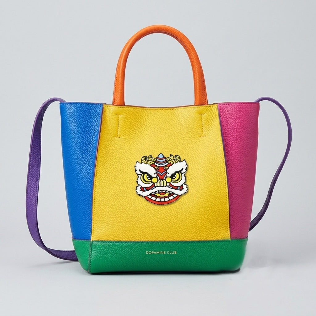 Chinese lion dance embroidered patch on a bold color-block leather tote bag