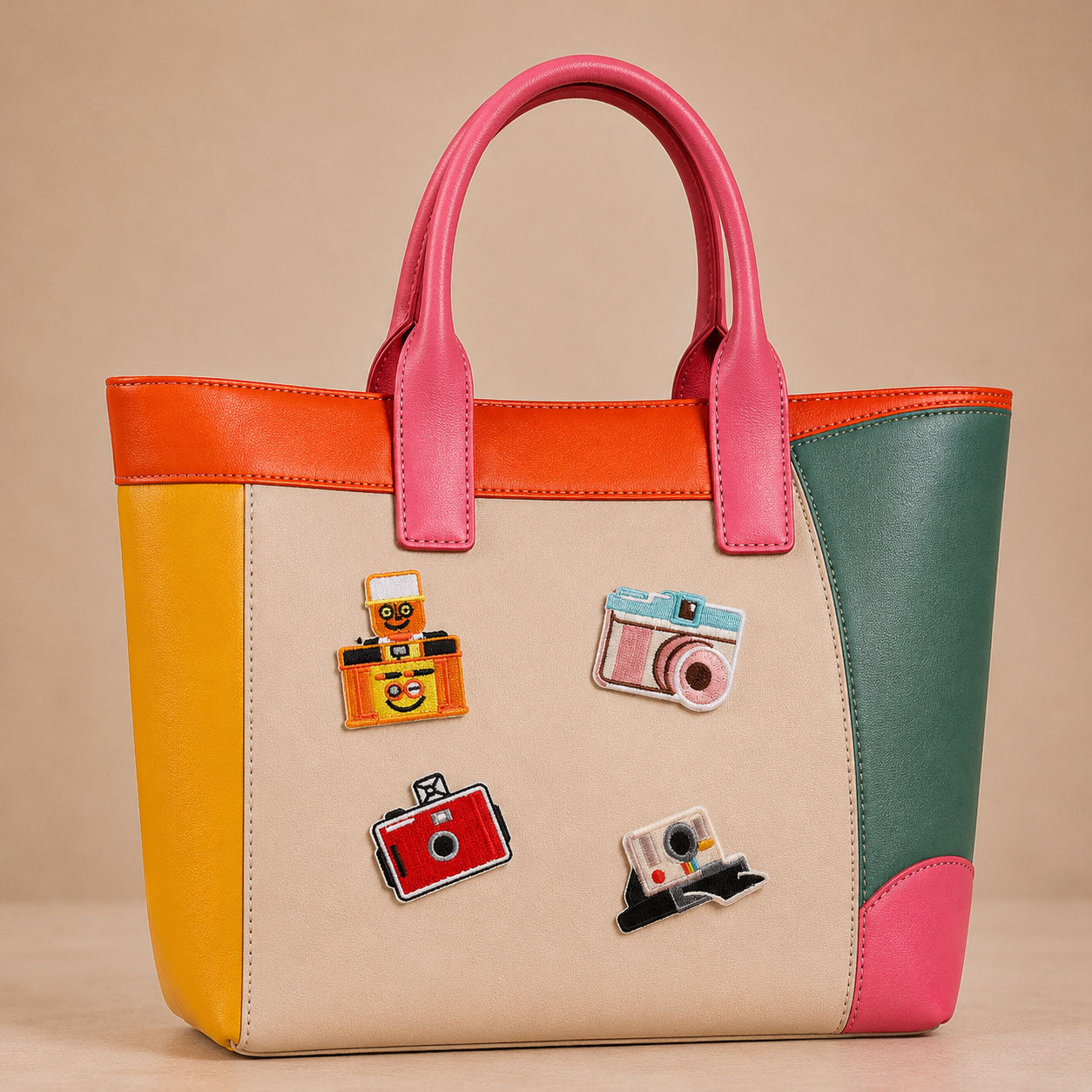 retro film camera polaroid and flash camera stick-on patches decorating a pink and orange color-block leather handbag