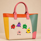 tomato eggplant apple daisy and lemon with legs stick-on patches decorating a pink and orange color-block leather handbag
