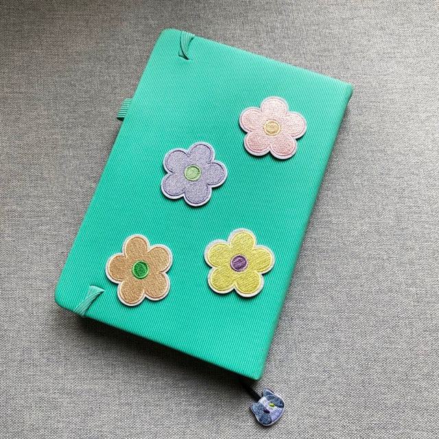 pastel macaron flower embroidered stick-on patch on a notebook