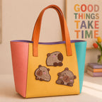 chubby capybara in various poses stick-on patches decorating a yellow and pink color-block leather handbag