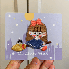 animated hand holding packaged the little witch embroidered patches showing two styles and detailed embroidery texture