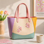 pink sakura flower stick-on patches decorating a cream and purple color-block leather handbag
