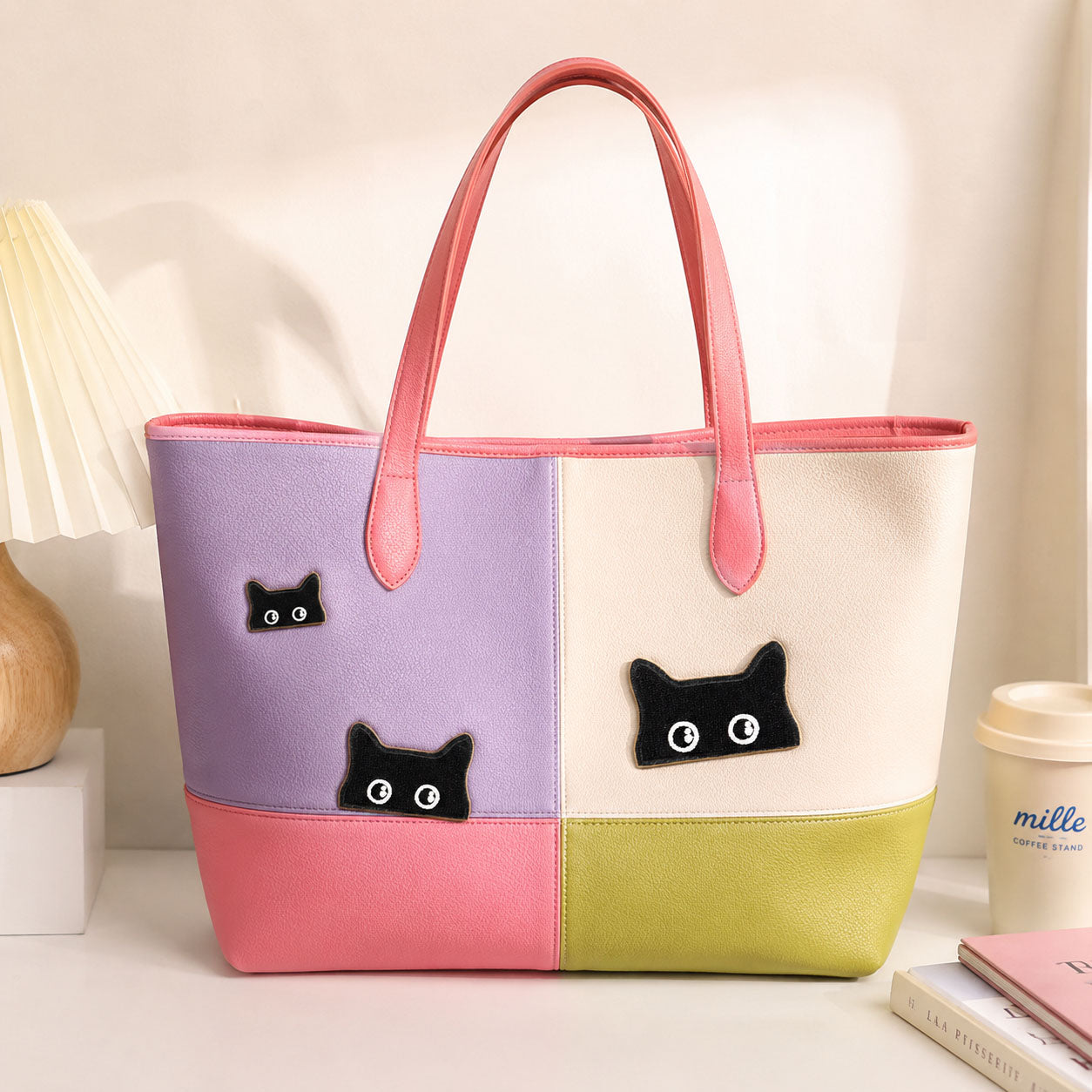 three peeking black cat embroidered patches on a pastel color-block leather tote bag