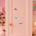 four cute cartoon dinosaur embroidered patches with triceratops t-rex brachiosaurus and stegosaurus stuck on a pink wardrobe door in a girls room