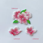 Three pink cherry blossom embroidered patches featuring twin blooms with leaves and two individual flowers
