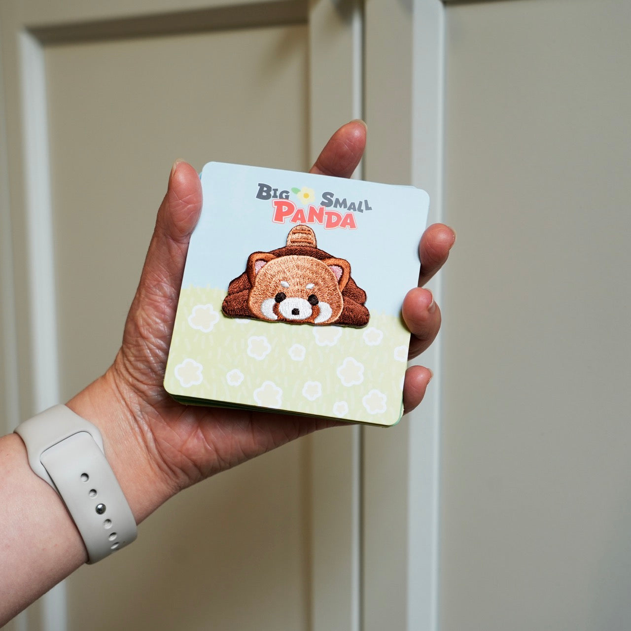 holding an adorable red panda embroidered stick-on patch