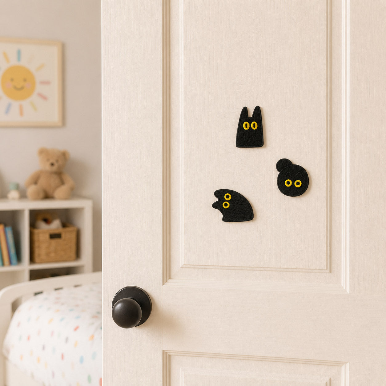 black cat face side profile and round silhouette stick-on patches with yellow eyes on a cream bedroom door at an angle