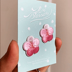 animated hand holding packaged oriental plum blossom embroidered patches showing three styles and detailed embroidery texture