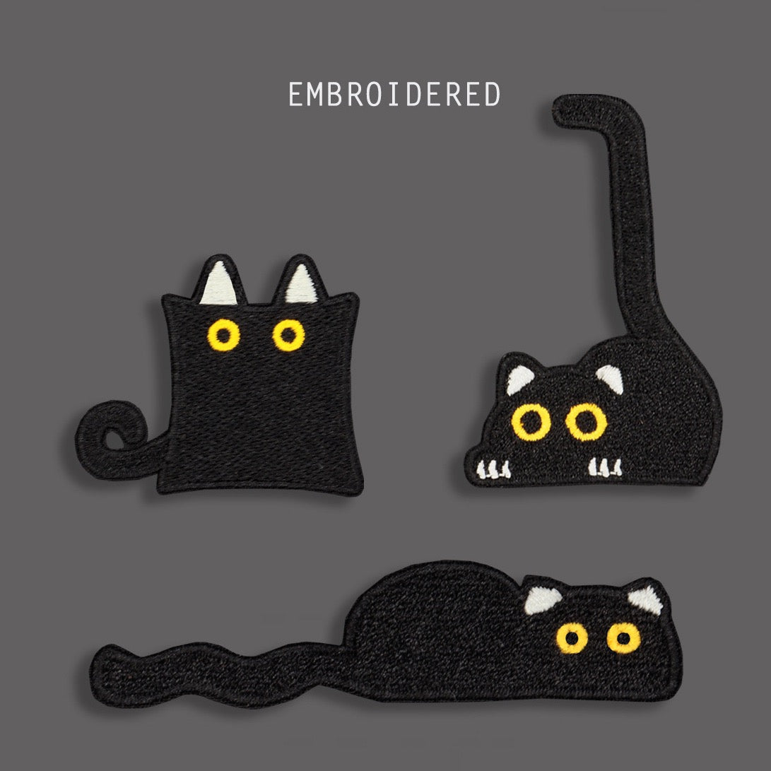 funny peeking black cat embroidered stick-on patches — three poses including tall tail peeking cat square sitting cat and flat loafing cat with bold yellow eyes on solid black
