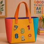 textured number and carabiner stick-on patches decorating an orange and yellow color-block leather handbag
