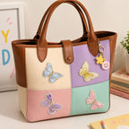 elegant gold trim butterfly stick-on patches in pastel colors decorating a color-block leather handbag