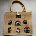 void black cat with pink accents embroidered stick-on patch on a jute tote bag