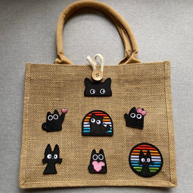 void black cat with pink accents embroidered stick-on patch on a jute tote bag