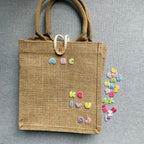 pastel alphabet embroidered patches spelling letters on a burlap tote bag with loose patches beside it