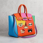 five vintage chenille cat and bear embroidered patches on a bold color-block leather handbag