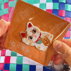 animated peel and stick demo of lucky beckoning cat maneki neko embroidered patch applied to a woven bag