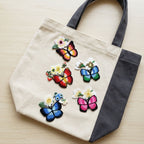 colorful butterfly with wildflower stick-on patches decorating a cream and grey canvas handbag
