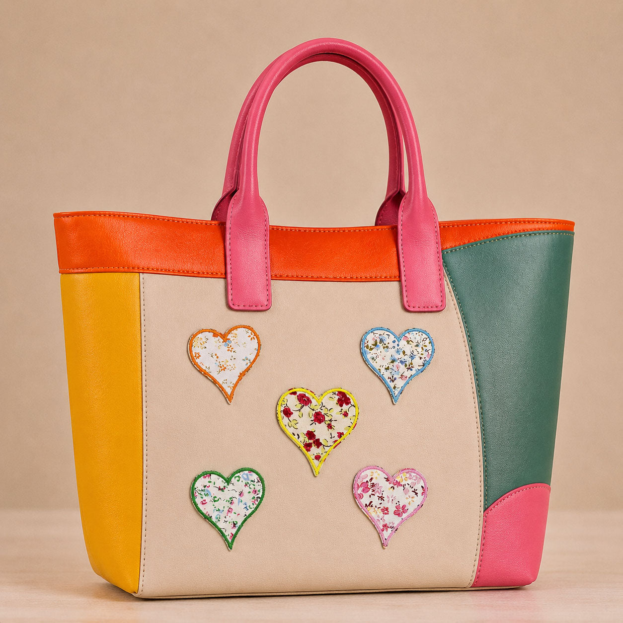 colorful floral print heart stick-on patches decorating a pink and orange color-block leather handbag