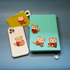 red panda embroidered patches on a card holder, phone case, and notebook