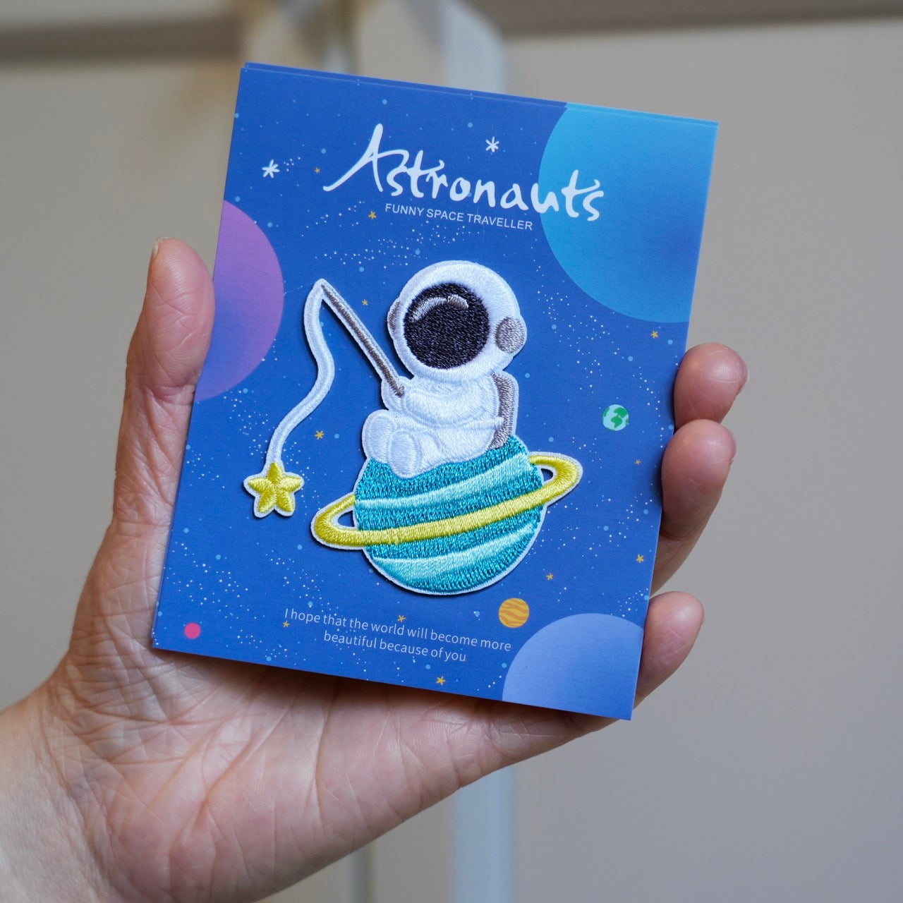 holding a kawaii astronaut embroidered stick-on patch in hand