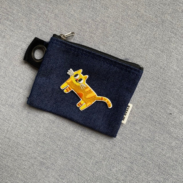 derpy orange cat embroidered patch on a dark denim coin pouch