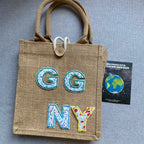 floral letter embroidered patches spelling GGNY on a burlap tote bag with product packaging card