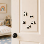 fluffy chenille panda back view rolling lying and stretching stick-on patches scattered on a cream bedroom door at an angle