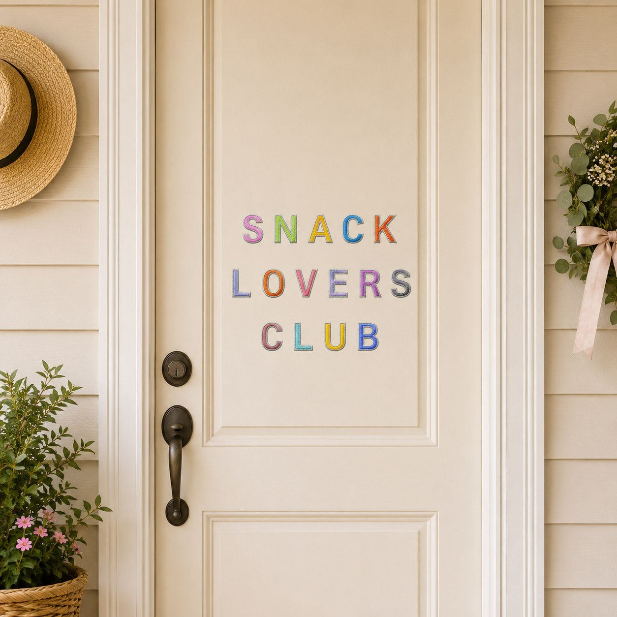 minimalist alphabet stick-on patches spelling snack lovers club in pastel rainbow colors on a white front door with wreath